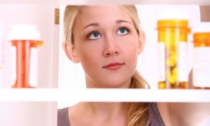 Female looking through medicine cabinet trying to clear space