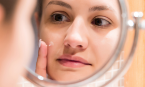 white female examining skin in the mirror